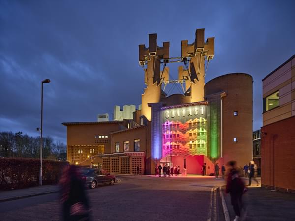Contact's castle-like building at night lit in rainbow colours
