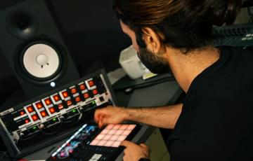 A young man mixes on equipment in a recording studio