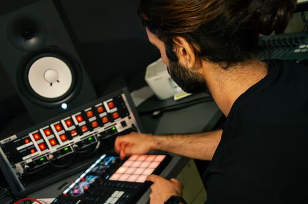 A young man mixes on equipment in a recording studio