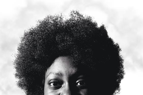 A black and white photo of a young person with an afro against a white background