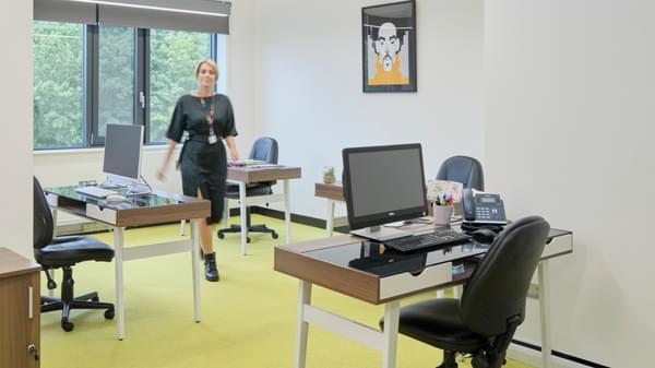 office space with desks and computers on them and a person walking through the middle of the office