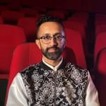 A British-Asian make in his 40s sat in a theatre auditorium
