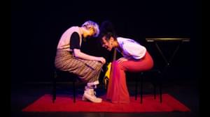 Two women sat facing each other, bending over and laughing.