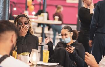 Two young people sit laughing in a cafe space