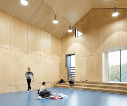 A bright studio space with wooden walls with 4 people rehearsing