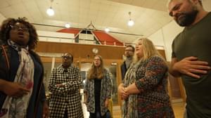 A diverse group of people stood in a studio space, singing.