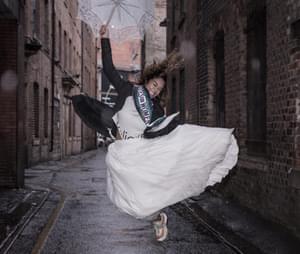 A young woman in suffragette clothes jumps in the street joyfully