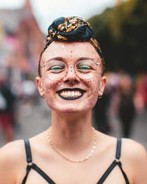 person smiling at the camera wearing glasses and back lipstick