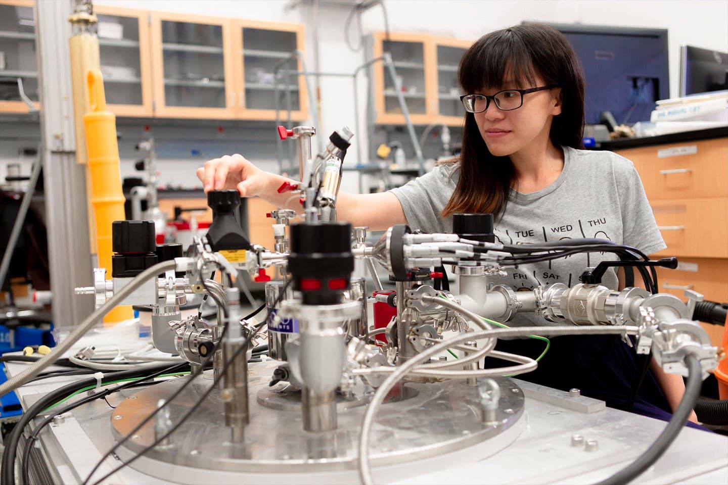 Individual standing behind and making adjustments to laboratory equipment