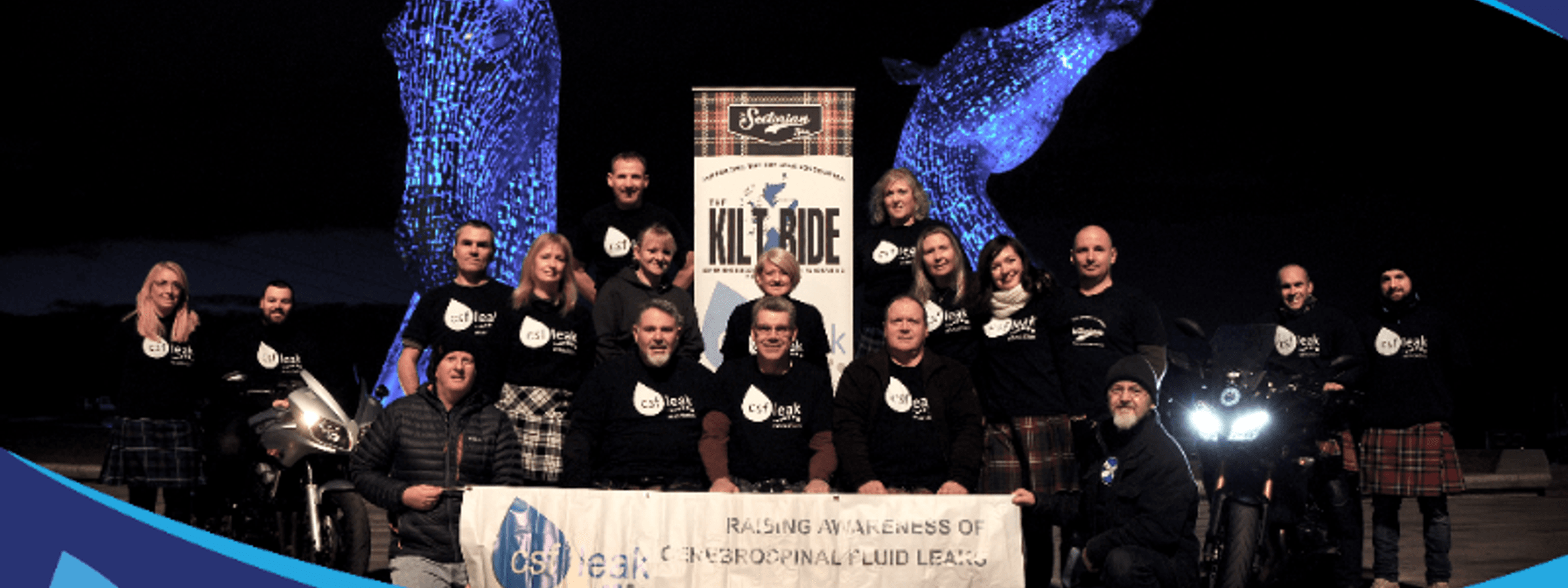 A group of people at the Kilt Ride event wearing CSF Leak Association shirts and holding a banner.