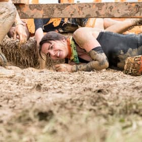 A woman on the ground in the middle of Tough Mudder.