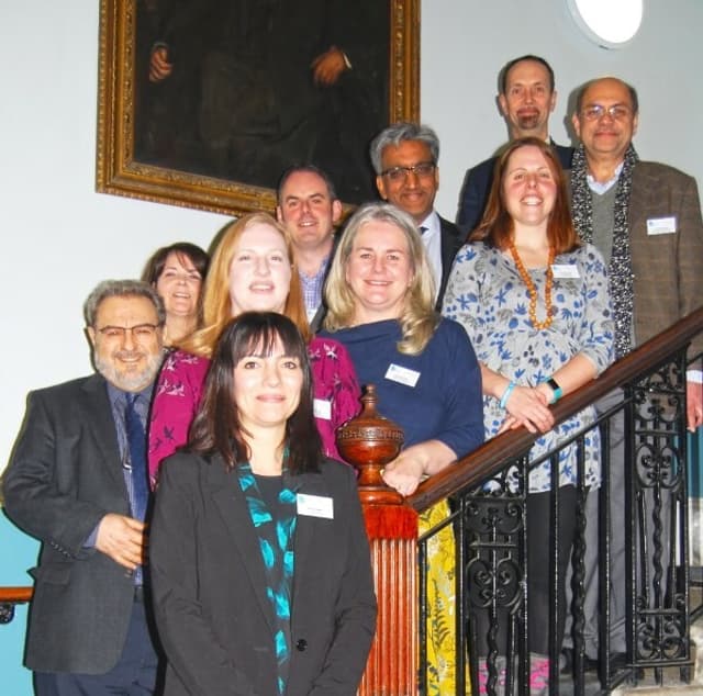 A portrait of a group of professionals with name tags standing on stairs.