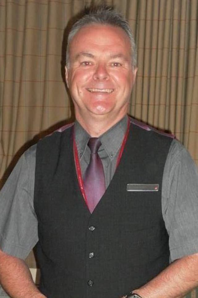 A portrait of an older male wearing his work uniform for Virgin Airways.