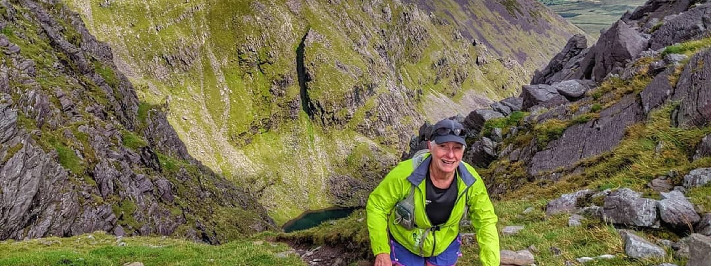 A woman hiking a steep mountain trail.