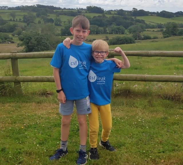 Two brothers with CSF Leak Association shirts, with the younger boy flexing his arm.