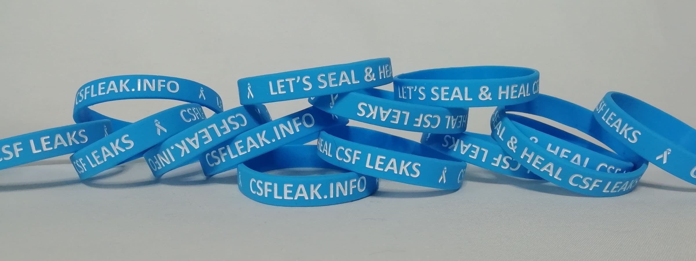 A pile of blue wristbands that say "CSFLEAK.info" on them.