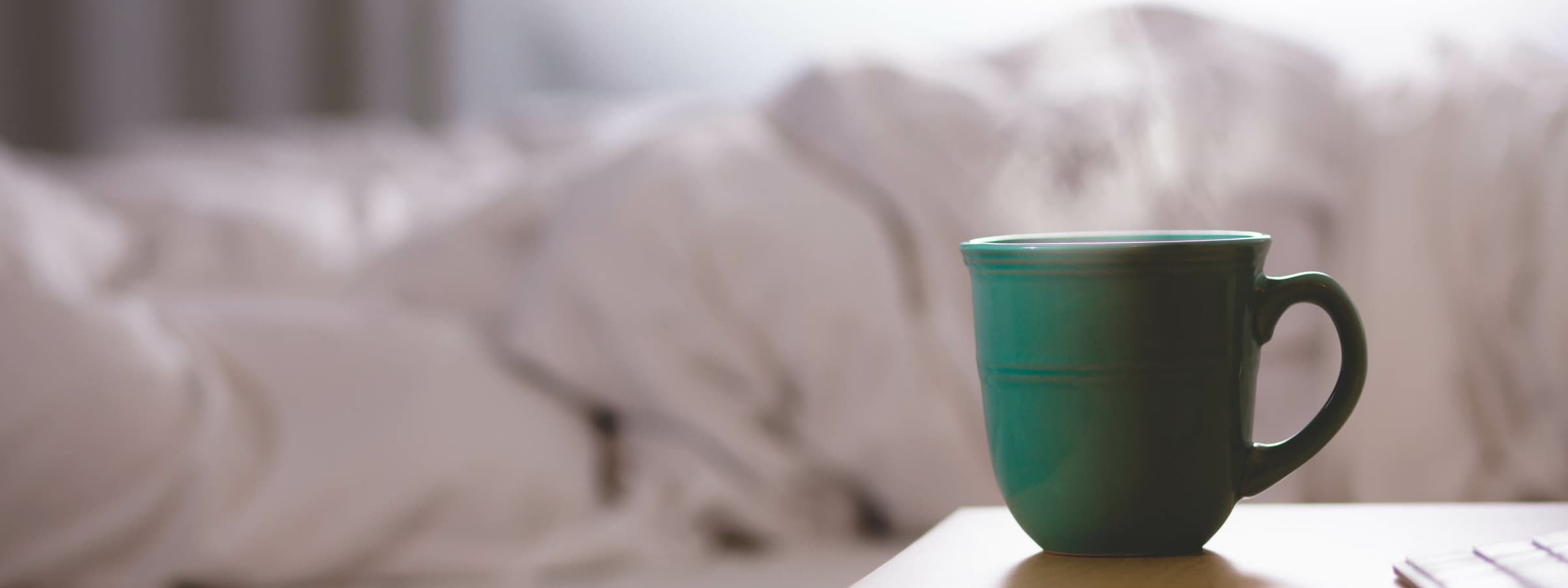 A mug on a nightstand with steam coming out.