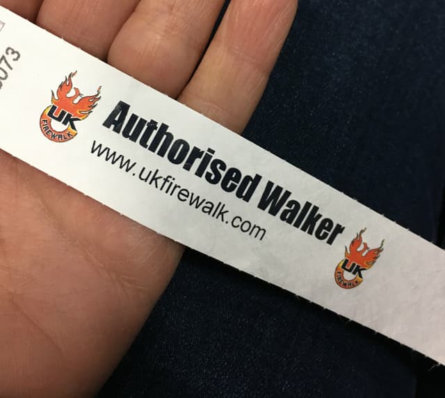 A wristband that says "Authorized walker" and "ukfirewalk.com".