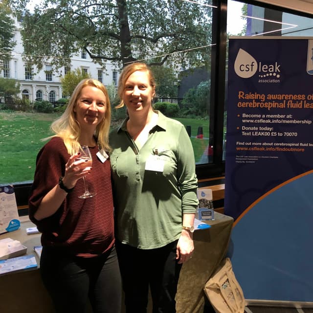 Dr. Gemma Pearce and Trustee Clare Joy in front of a CSF Leak Association booth at an event.