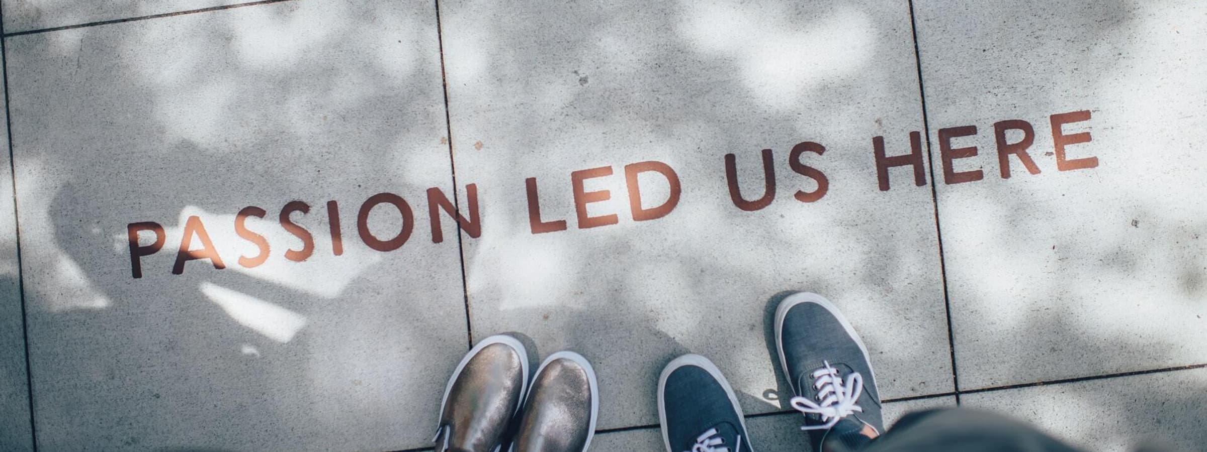 Two pairs of shoes with the text "Passion led us here" on the ground.