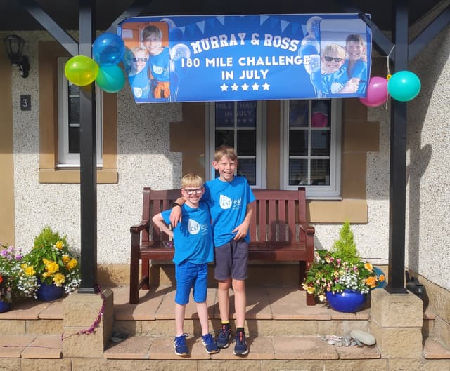 Two young brothers smiling under a banner that says "Murray & Ross 180 Mile Challenge."