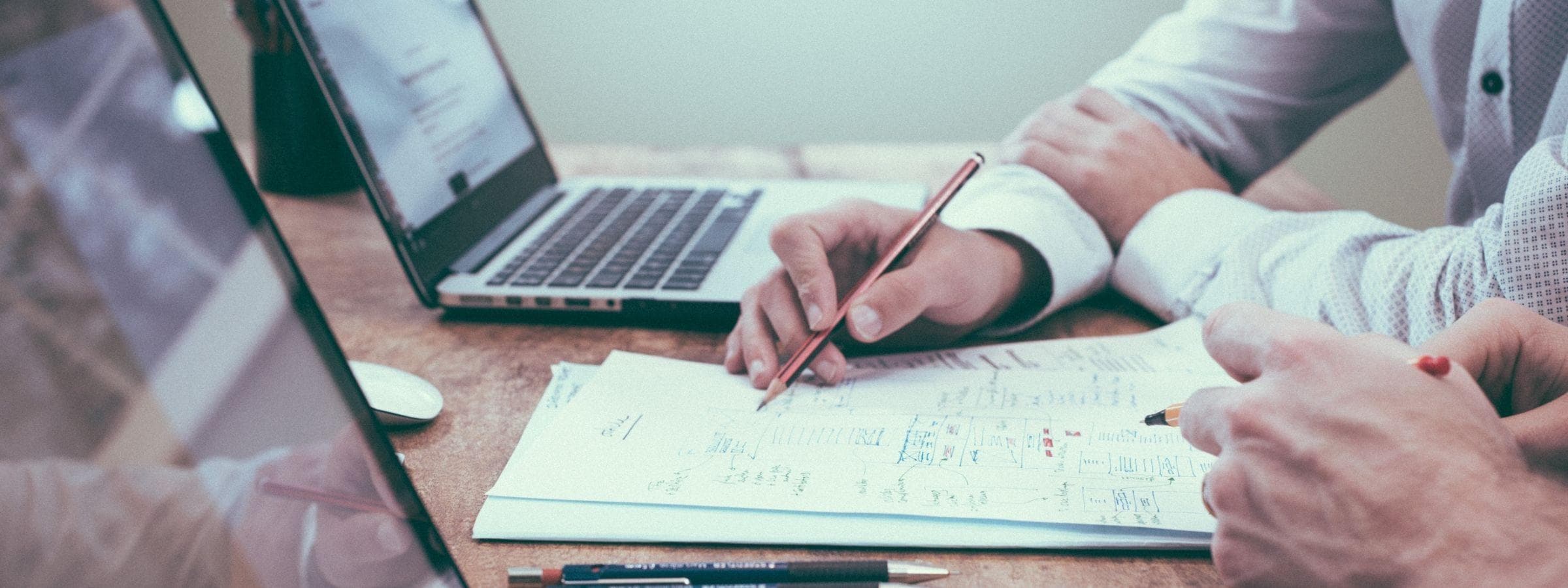 A man writing on paper and working on his laptop.