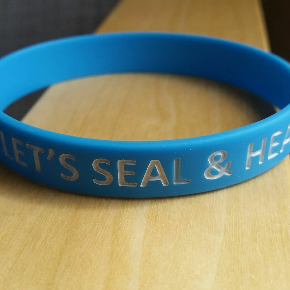 A blue wristband that says "Let's seal & heal".