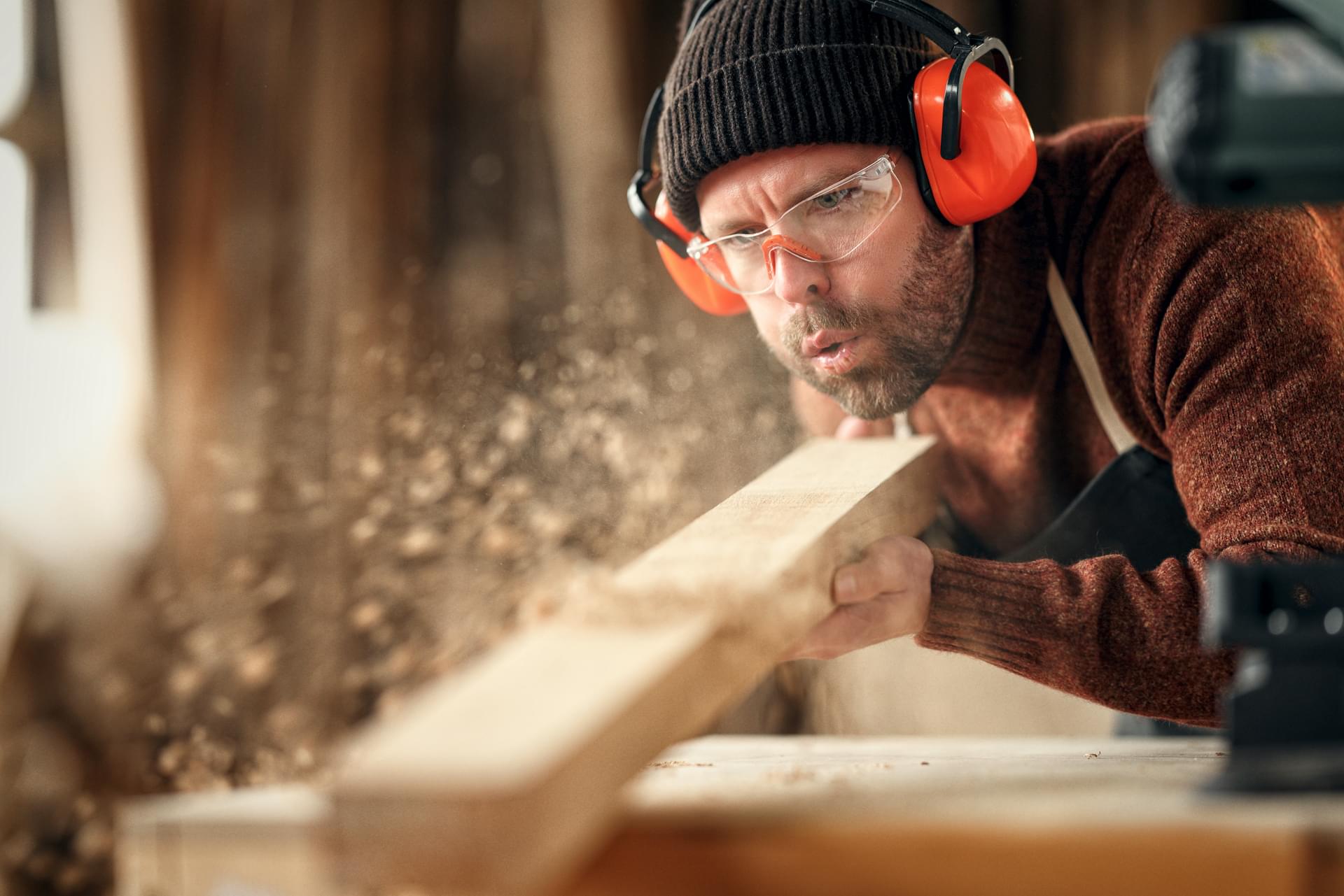 Handwerker Schreiner pustet Holzspäne