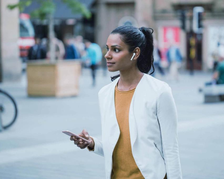 A woman walking on the street using her phone.