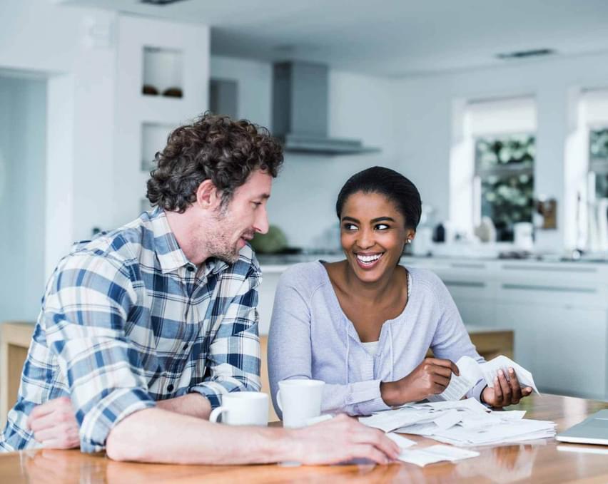 A woman and man confidently looking at financial documents while drink coffee.