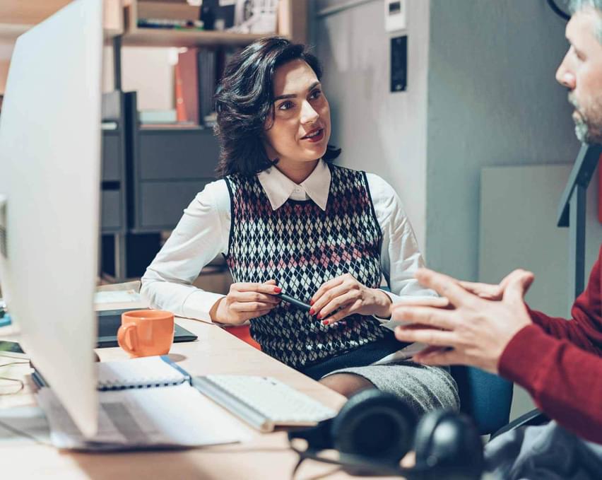 A man and a woman working in front of a computer.