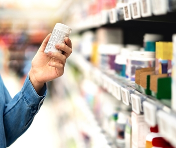 person holding a pill bottle in pharmacy