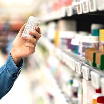 person holding a pill bottle in pharmacy