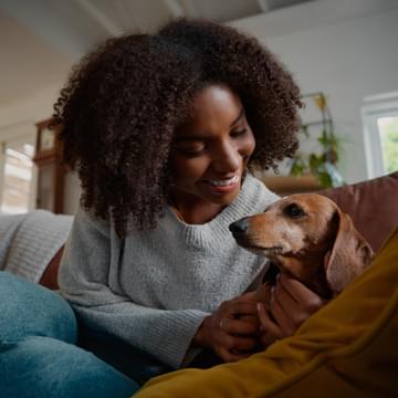 woman on brown couch with pet daschund