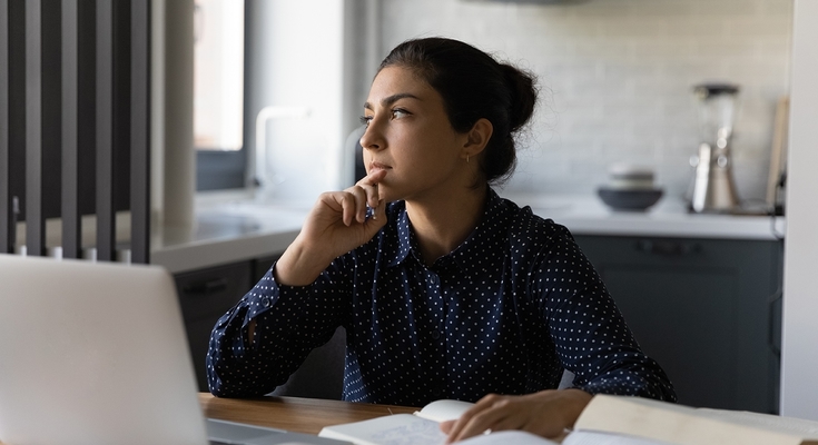 woman at laptop brown hair looking out window