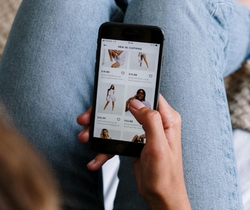 Woman sitting down, holding iphone while online shopping for clothes