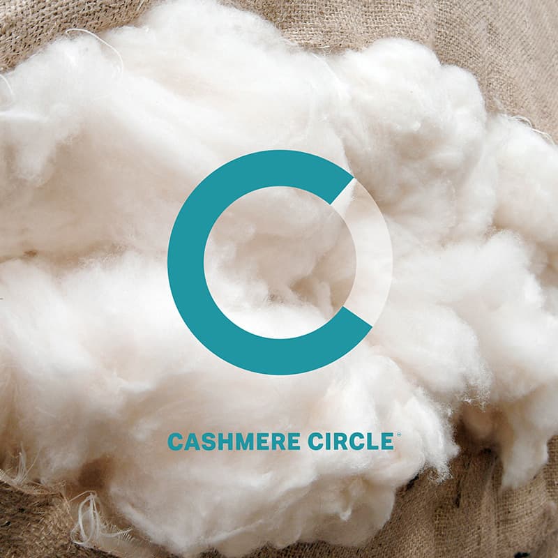 Johnstons of Elgin X Cashmere Circle logo overlaid on a hessian sack containing white cashmere fibres