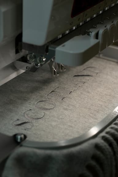 Johnstons of Elgin embroidering silver cashmere throw with text on embroidery machine