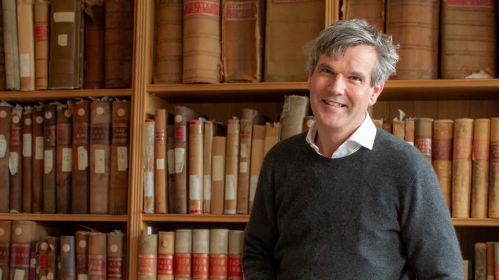 Interior Designer Ben Pentreath with archive books behind