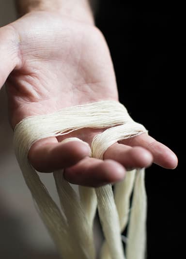 Cashmere Yarn draped over a hand intwining with fingers