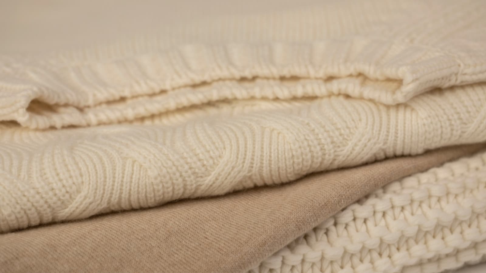 Johnstons of Elgin Cashmere Sweaters in a stack of cream cable, ecru cable and beige knitwear