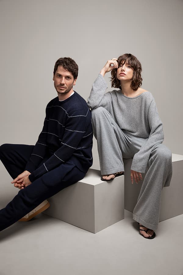 Johnstons of Elgin Cashmere Knitwear in navy and grey being worn by two models against a grey studio background