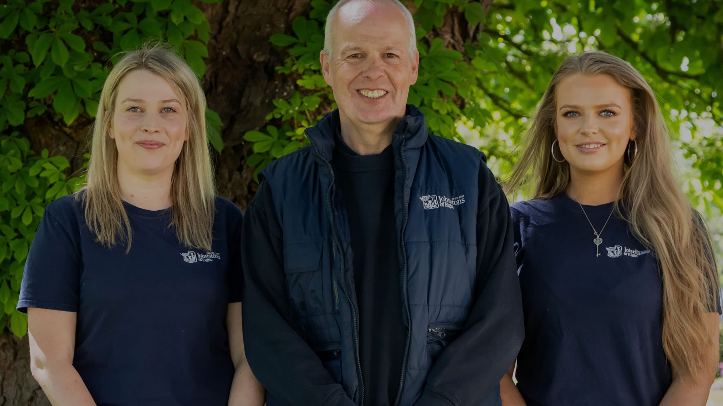 Mike Mathieson and his daughters all in Johnstons of Elgin uniform in front of a chestnut tree