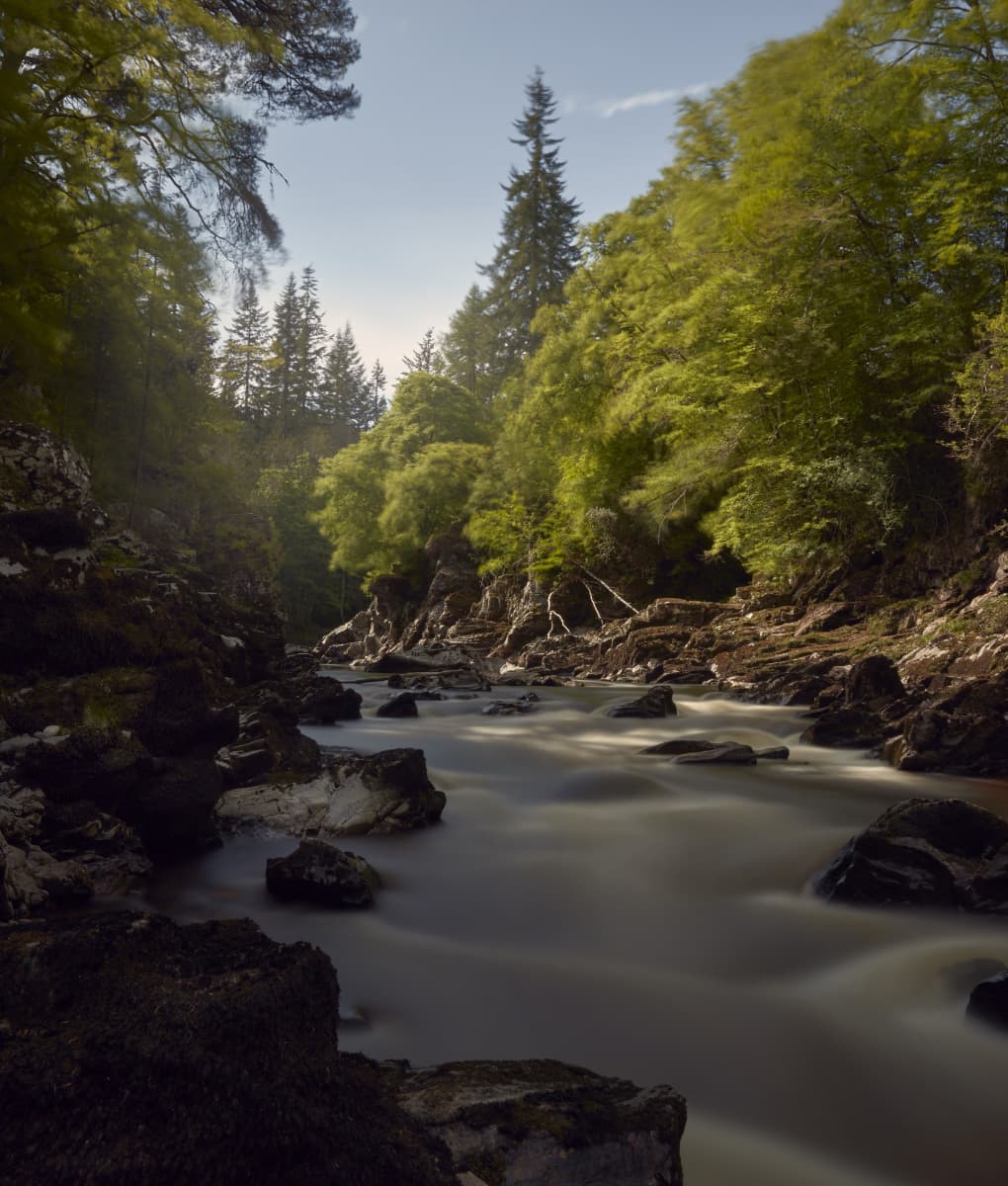 Image on Johnstons of Elgin website of a river flowing through green tree lined land
