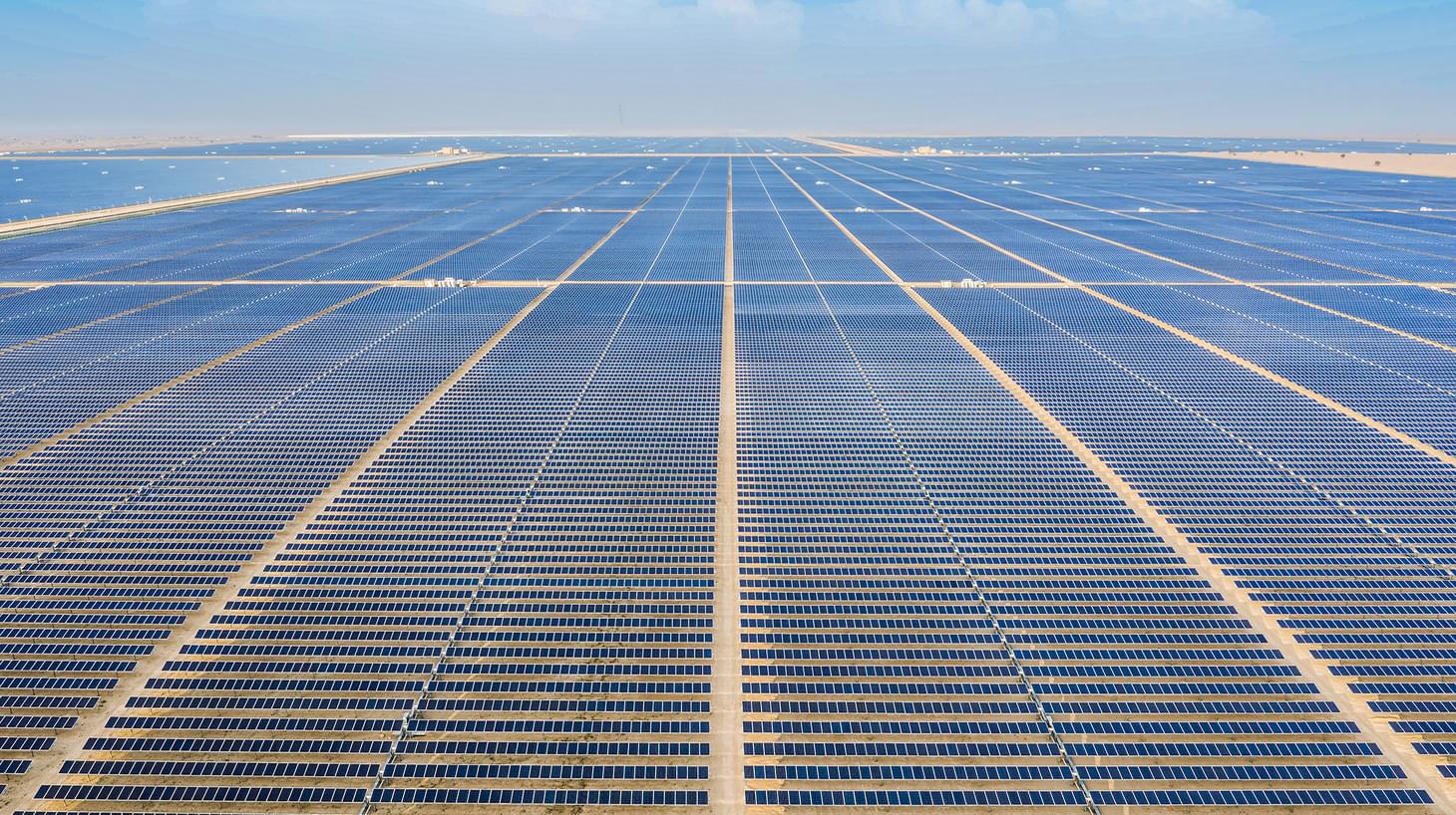 A desert scape that extends far in to the distance covered with hundreds solar panels.
