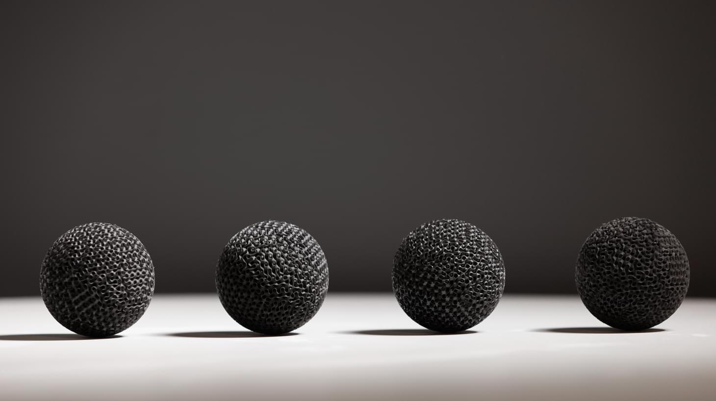 A close up image of four 3D printed metal spheres resting on a table