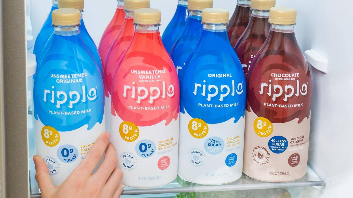 Different types of Ripple plant-based milk lined up on the shelf of a fridge
