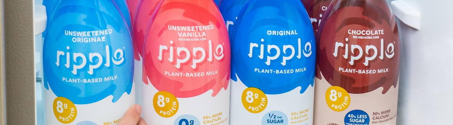 Different types of Ripple plant-based milk lined up on the shelf of a fridge