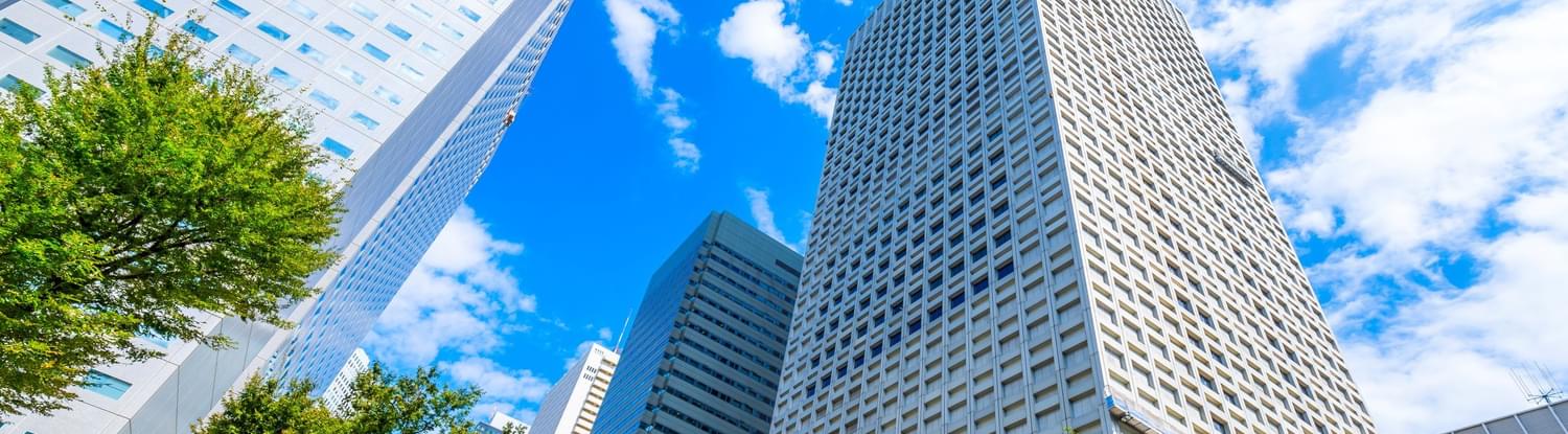 A cityscape image, looking up at tall buildings from the street level