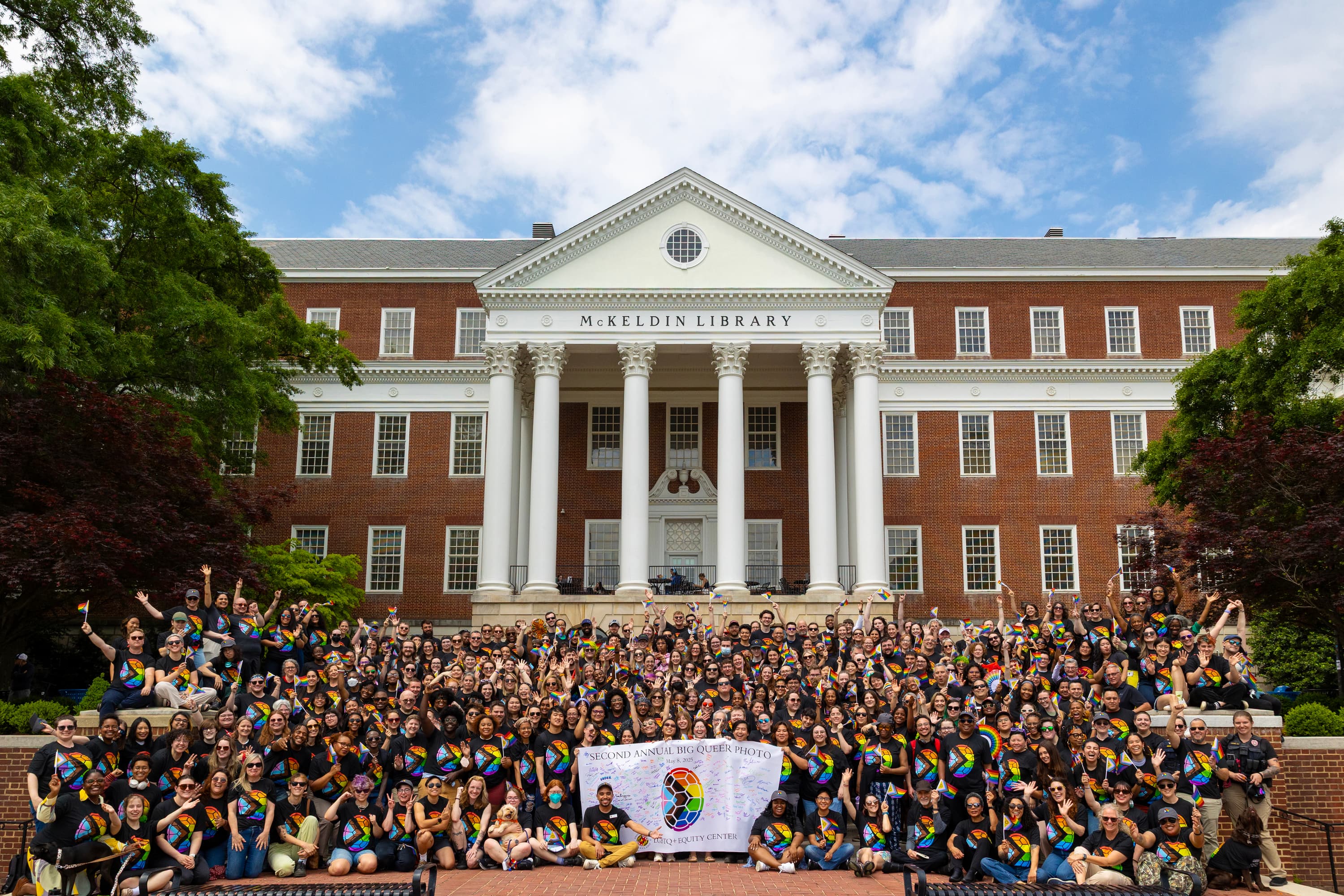 2nd Annual Big Queer Photo with more than 300 participants smiling and holding the signed Big Queer Photo Banner.